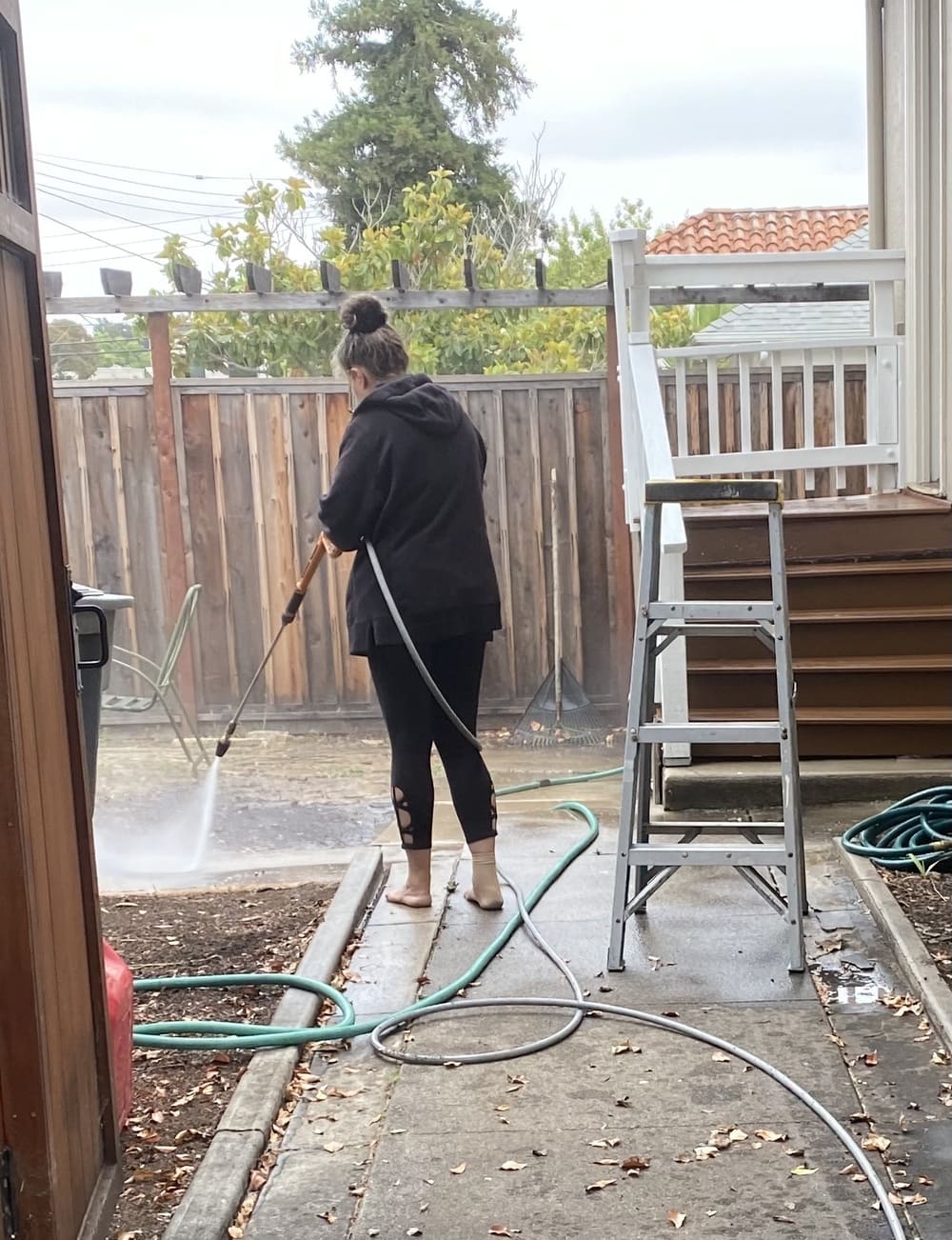 A woman operating a pressure-washer and cleaning the ground